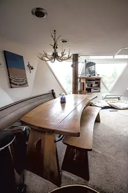 A salvaged church pew serves as a bench for a curved kitchen table. - TOM MCNEILL