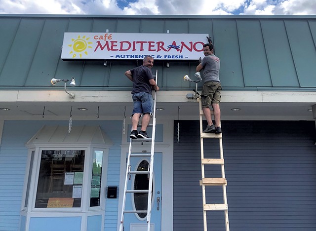 Cafe Mediterano owner Barney Crnalic (left) and friend, Mehmed Tuco, hang the sign at the new location. - COURTESY OF CAFE MEDITERANO