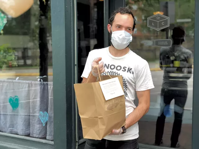Logan Bouchard handing off an order curbside from Misery Loves Co.'s "Digital Delicatessen" - JORDAN BARRY ©️ SEVEN DAYS