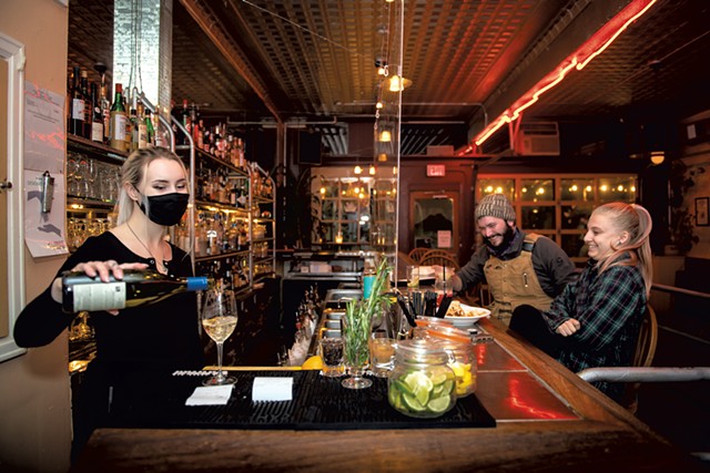 Bartender Gabriana Whiting (left) serving drinks, while Matt Cote-Wurzler of Shelburne and Maddie Marchionna of Burlington sit at the bar at the Daily Planet - DARIA BISHOP