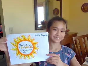 Sophia Oszurek with a colorful sign made to cheer up neighbors and passersby - MARY JANE OSZUREK