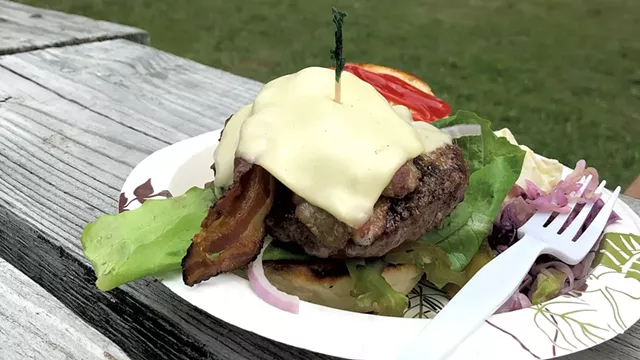 A burger on a picnic table overlooking the lake - STINA BOOTH