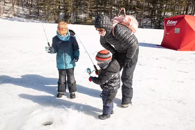 Sam Coleman helps his sons, George, 3, and Charlie, 8, ice fish with a jigging rod. - CAT CUTILLO