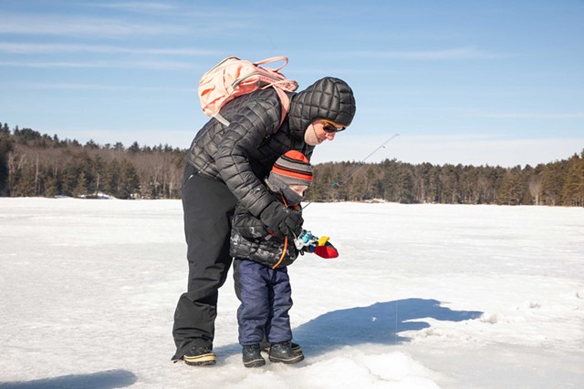 Sam Coleman helps his 3-year-old son, George, ice fish with a jigging rod. - CAT CUTILLO