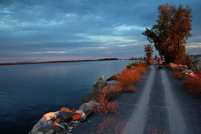 Sarah pulls Elise in a bike trailer along the Island Line Trail at sunset - TRISTAN VON DUNTZ
