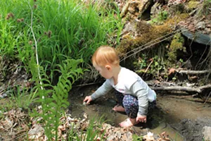 Elise takes a break from trail work to play in a stream - SARAH GALBRAITH