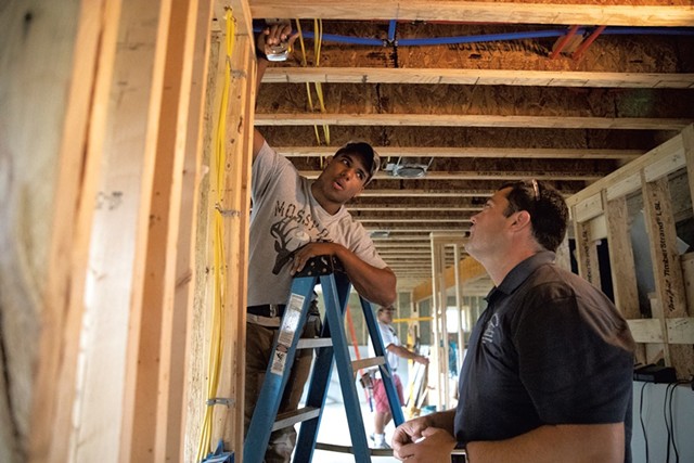 Essex High School senior Keshon Peters (left) and instructor Chris Welch discuss the measurements needed to cut ceiling drywall to fit around a corner - JAMES BUCK