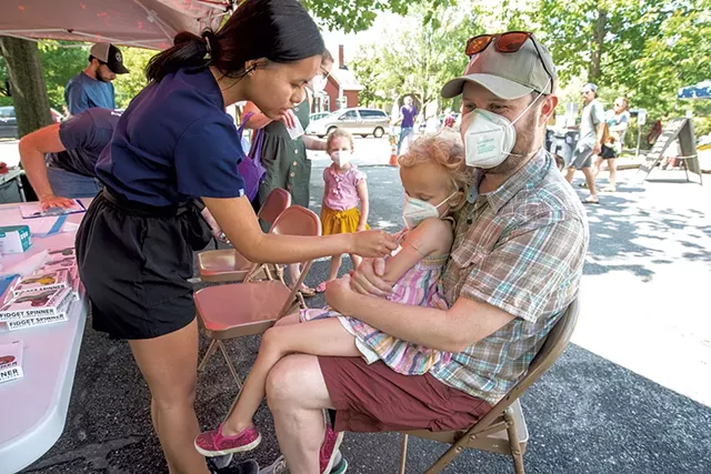 Tristan McNamara holding his daughter Lyra, 4, as she receives a COVID-19 vaccine from nurse Jenna Doran - JEB WALLACE-BRODEUR