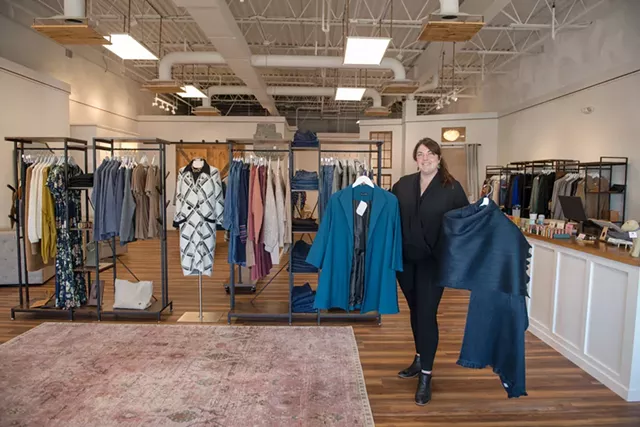 Store manager Samantha Sleeper holding an Estelle and Finn swing coat and an alpaca wrap by Pokoloko - DARIA BISHOP