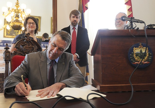 Gov. Phil Scott, surrounded by journalists, signs the shield bill into law. - JEB WALLACE-BRODEUR