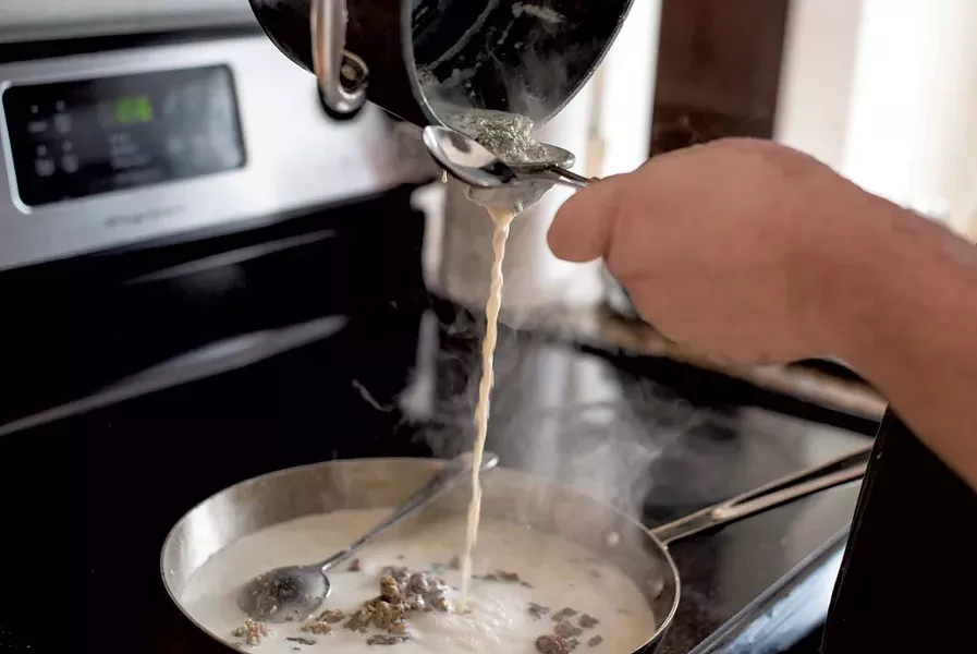 "Bobby" pouring marijuana flower-laced milk as he makes cannabis-infused sausage and gravy - GLENN RUSSELL