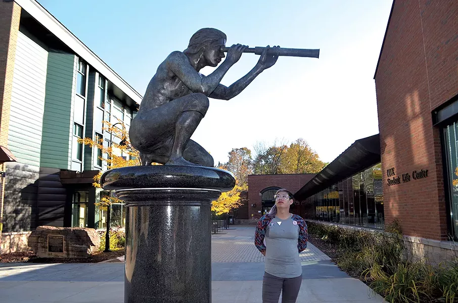 Jayy Covert standing next to the sculpture of Samuel de Champlain at Champlain College - MOLLY WALSH