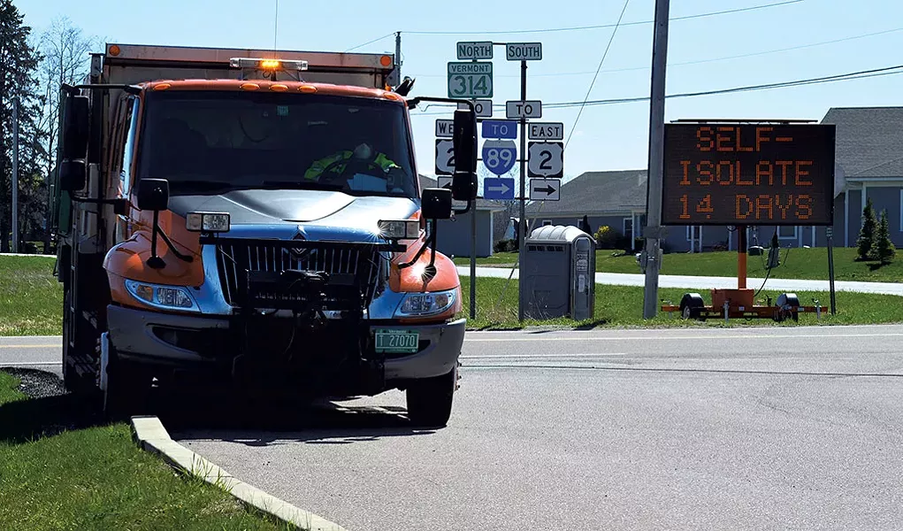Vermont Agency of Transportation employee tracks license plates coming off the Grand Isle ferry near a sign delivering the governor's message - SASHA GOLDSTEIN