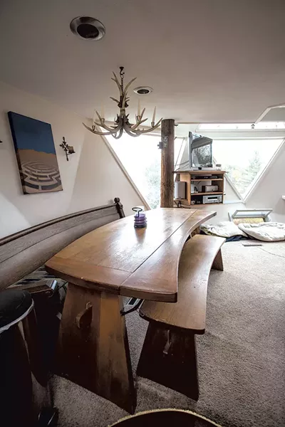 A salvaged church pew serves as a bench for a curved kitchen table. - TOM MCNEILL
