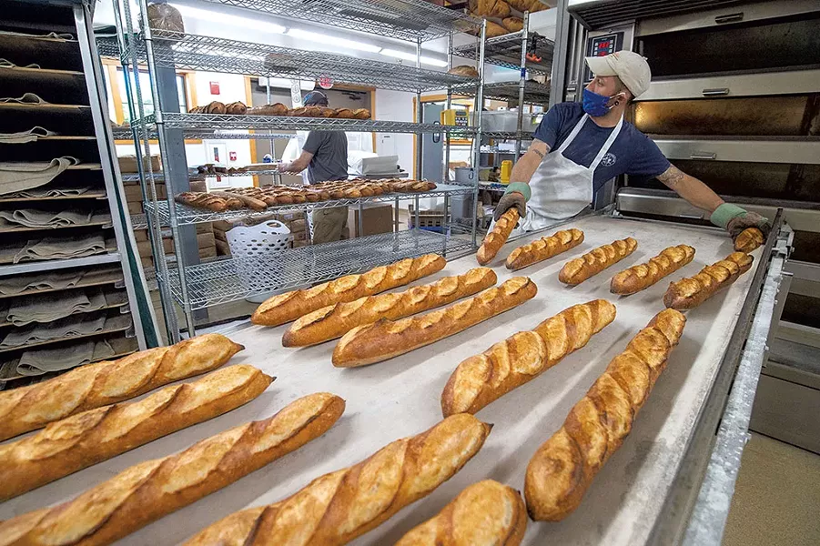 Baker Marc Levy removing fresh-baked baguettes from the oven - JEB WALLACE-BRODEUR