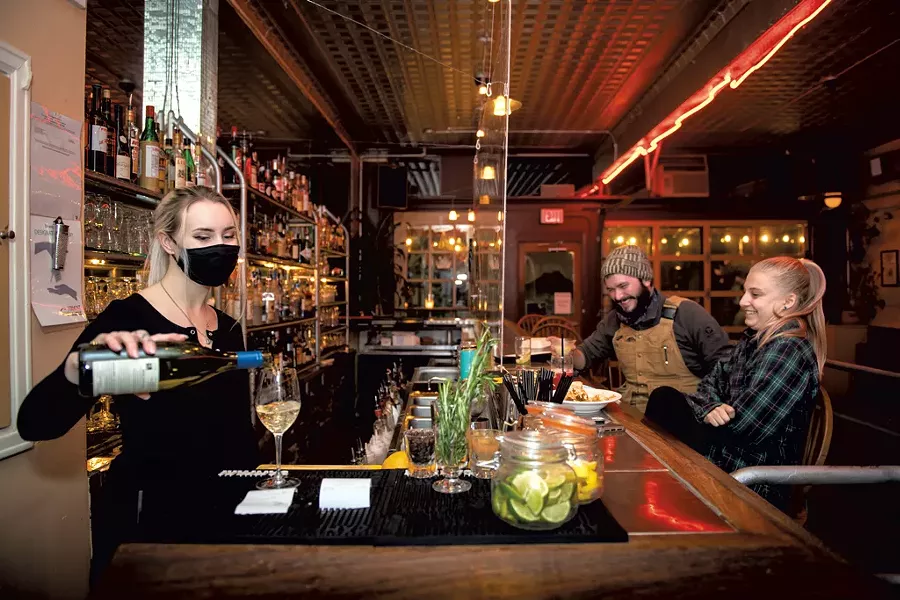 Bartender Gabriana Whiting (left) serving drinks, while Matt Cote-Wurzler of Shelburne and Maddie Marchionna of Burlington sit at the bar at the Daily Planet - DARIA BISHOP