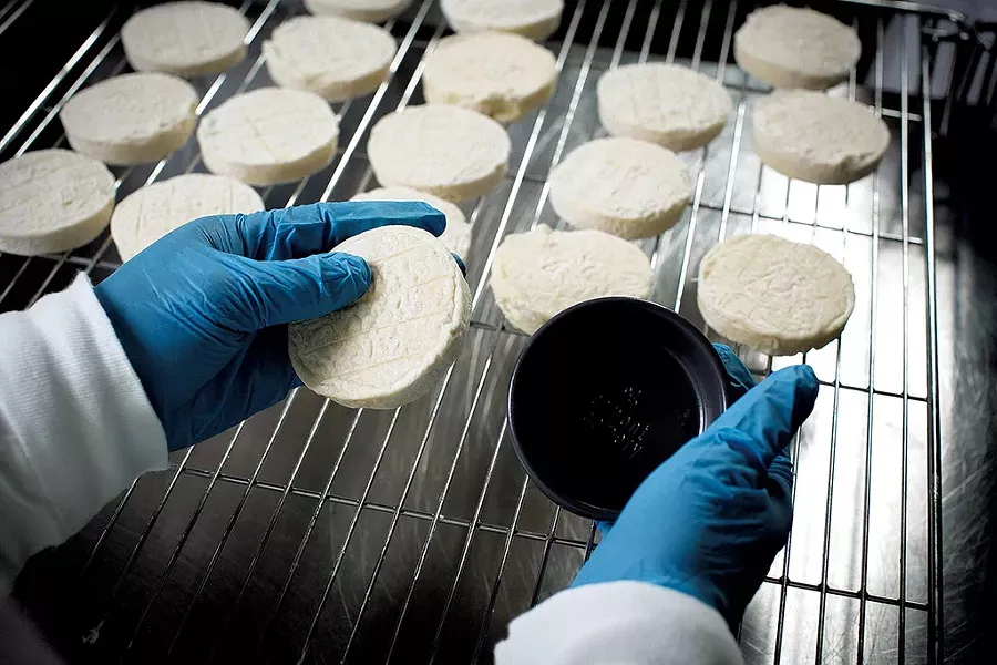 A worker packaging St. Albans cheese in a clay crock - COURTESY OF BRENT HARREWYN