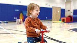 Riding on a toddler bike in the gymnasium during family recreation time at the YMCA.