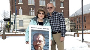 Betty and Chris Barrett holding a photo of their son, Michael, who killed himself in 2004