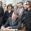 Gov. Phil Scott, joined by his wife Diana McTeague Scott, signs the bills into law amid a mixture of applause and jeers. Gov. Phil Scott, joined by his wife Diana McTeague Scott, signs the bills into law amid a mixture of applause and jeers.