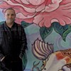 Brian Lewis in front of a mural by Tara Goreau at Filling Station