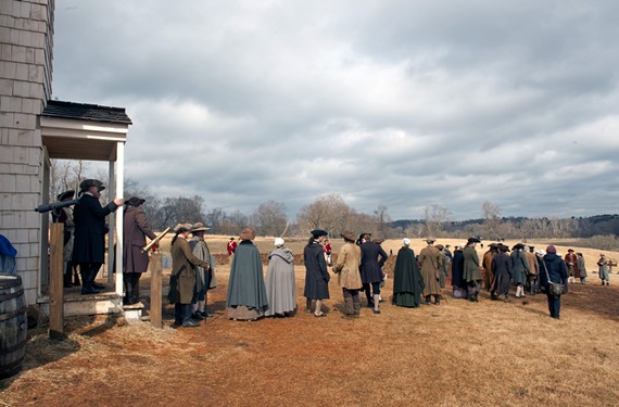 A few hours after a downpour on a cold day in late February, a line of background actors prepares for a sweeping shot on the set of “Turn,” west of Richmond. Just over the hill to the right is the set for Setauket, which appears onscreen as a small, coastal town. - SCOTT ELMQUIST