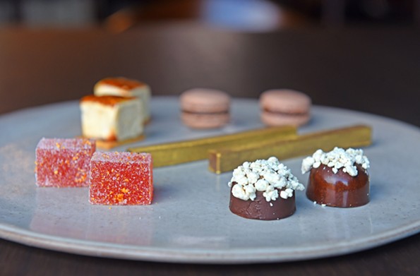 Miniature sweets known as mignardises, clockwise from top: chocolate-rosemary macarons, black sesame toffee gold bars, cauliflower bonbons, whiskey pâté de fruit with smoked sugar and ras el hanout marshmallows. - SCOTT ELMQUIST