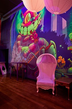Alice in Wonderland-inspired decor includes a mural of the Cheshire Cat and whimsical furniture. - TYLER DARDEN