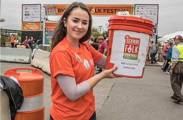 A bucket brigade volunteer holds up one of the orange containers in 2017.  This year there will be a texting option to donate as well. - DAVE PARISH PHOTOGRAPHY