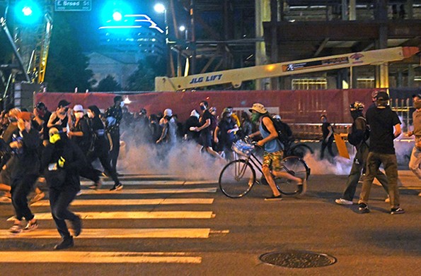 Protesters scatter after police threw tear gas into the crowd near City Hall on Sunday evening. - SCOTT ELMQUIST
