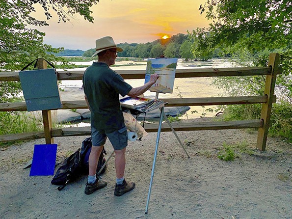 A man paints the river at sunset.