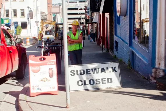 A construction worker blocks the sidewalk to Blowers Street businesses - STOO METZ