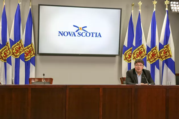 Chuck Porter, the minister of municipal affairs and housing announces to an empty room and reporters on the phone that the government is bringing rent control back—27 years after it got rid of it.