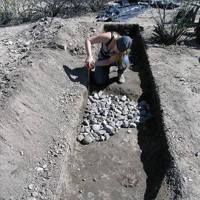 Photo of partly excavated Hohokam horno (earth oven) with heating stones at University Indian Ruin