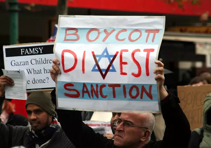 A protestor holds a sign in support of the Boycott Divest Sanction movement against the Israeli government. - WIKIMEDIA COMMONS