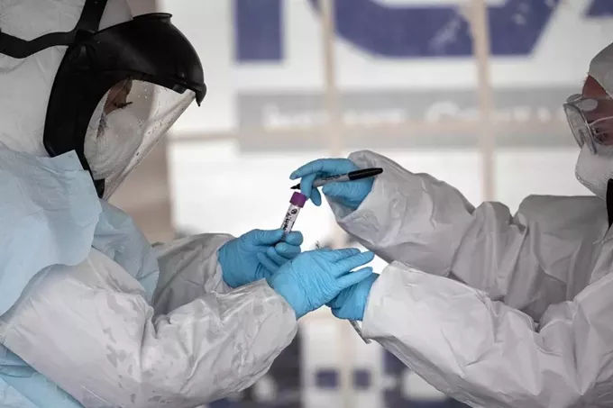 Health workers dressed in personal protective equipment handle a coronavirus test at a drive-through testing station in Stamford, Connecticut. (John Moore/Getty Images) - PROPUBLICA