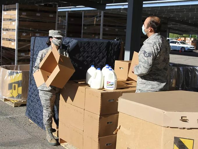 National Guard troops have a conversation while opening boxes of milk during a drive-thru food bank at Kino Stadium located at 2500 E Ajo Way. - AUSTIN COUNTS