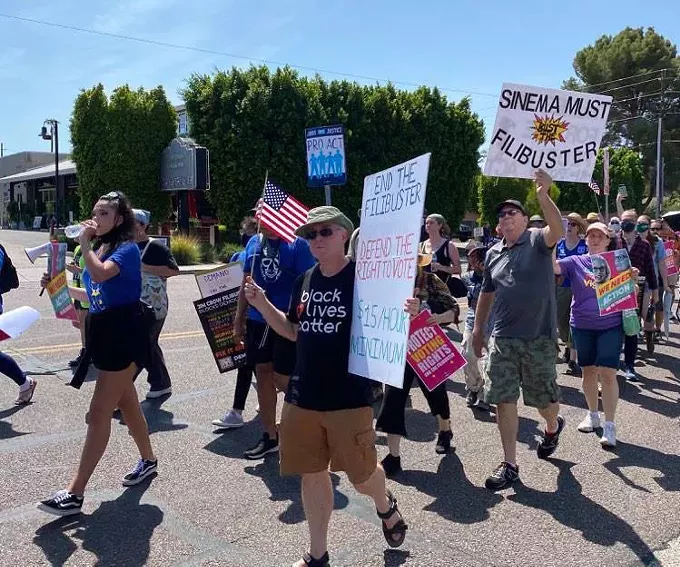 Protestors hold signs advocating for ending the Senate filibuster, increasing the federal minimum wage to $15 an hour, protection of voting rights and defending the right to vote. - EMMA ASCOTT/CRONKITE NEWS