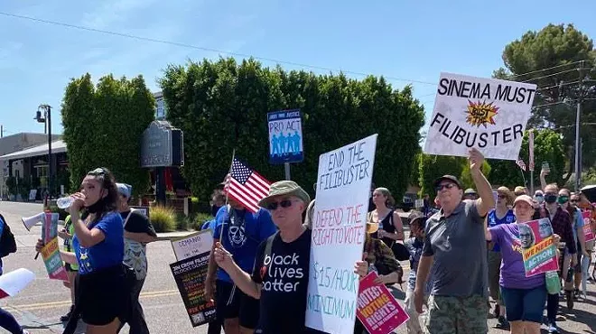 Protestors hold signs advocating for ending the Senate filibuster, increasing the federal minimum wage to $15 an hour, protection of voting rights and defending the right to vote.